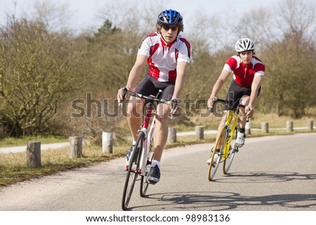 Two cyclists leaning inwards in the curve of a road during a training tour on a sunny spring day