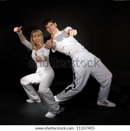 Creative shot of couple doing break-dance and showing positivity. Not isolated. Light shadows on the walls.
