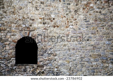 ark window in old stone wall of a medieval dungeon (old fortress)
