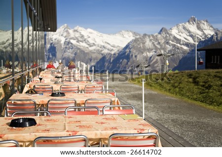 mountain restaurant under the sunlight and with snowy peaks on a background. In expectation of visitors