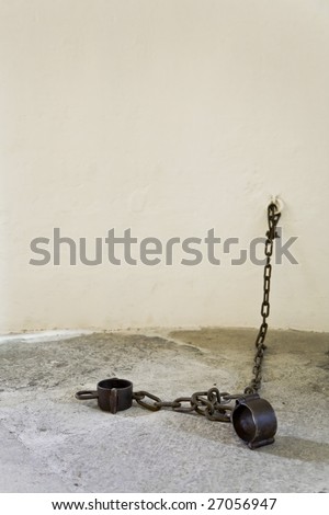the cell in prison and shackles fixed(attached) to a freshly painted stone wall