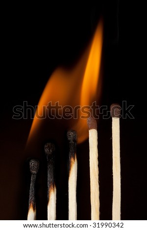 Burning matches close-up over black background (expantion concept)