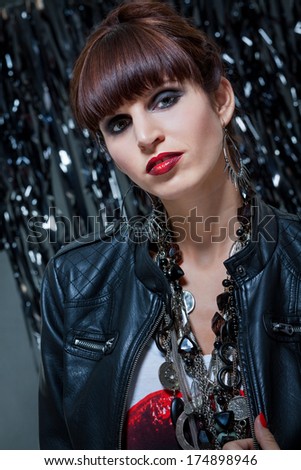 Beautiful glamorous sexy woman with her brunette hair cut in a fringe wearing trendy jewellery looking at the camera with parted red lips against a bokeh background