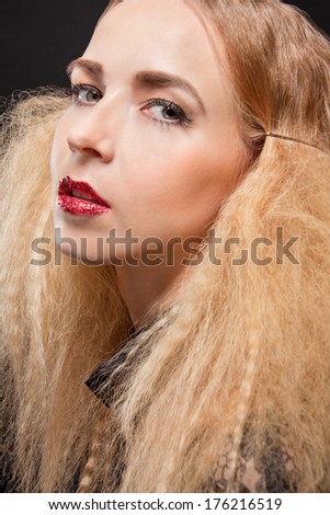 Beautiful seductive blond woman with red parted lips and a sultry expression looking sideways at the camera with an inviting glance