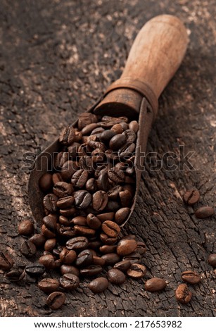 old measuring scoop with coffee beans on old wooden background