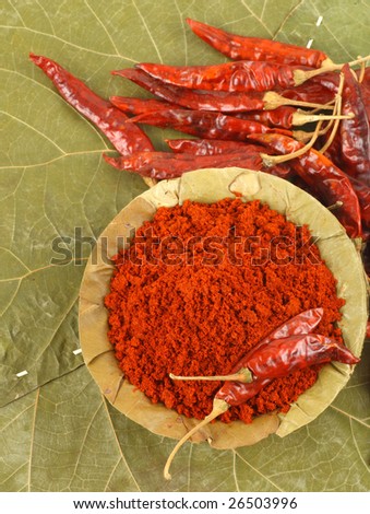 Bowl of chillies powder on dry leaf background
