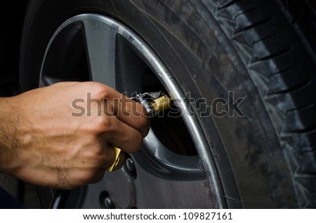 man refilling air into a car tyre