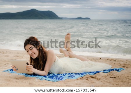 asian lady playing tablet on the beach