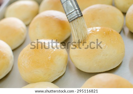 daubing butter to baked bun for shine its surface