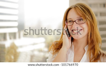 Young red hair business woman is  on the phone and smiling while doing business