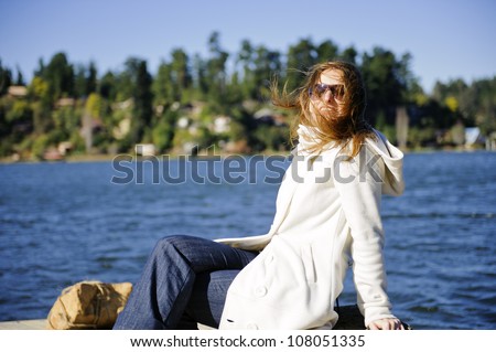 Very natural and beautiful girl on vacations posing in a windy morning at the lake
