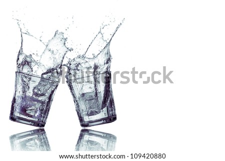 Splashing water from two glasses isolated in white
