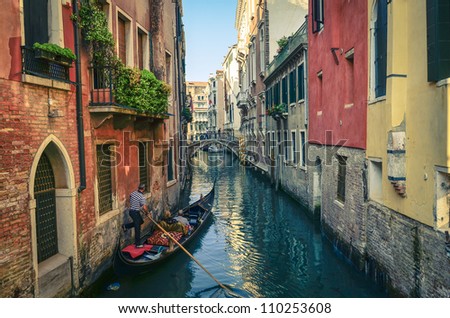 Classical picture of the venetian canals with gondola across the canal.