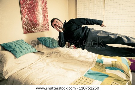 Funny shot of a man thinking but flying over his bed.