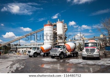 Concrete company and three mixer trucks in a blue sky day.