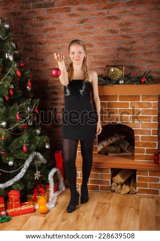 Beautiful woman in little black dress  holding Christmas sphere in hand