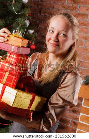 Smiling blonde woman in business attire with pile of Christmas presents