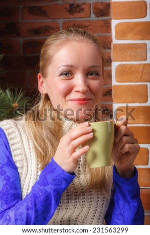 Close up of beautiful woman in  blue lace blouse and white knitted tunic with mug of coffee
