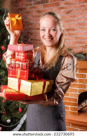 Smiling woman in business attire holding big pile of Christmas presents