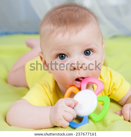 Baby lying on his belly with teether in the mouth