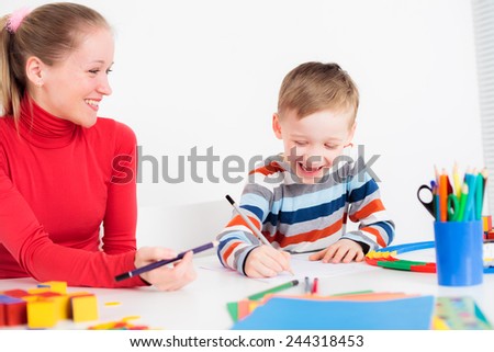Mother and son drawing together, child laughing happily