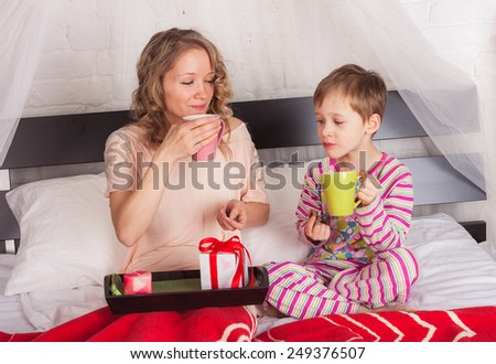 Beautiful woman with her son drinking tea in bed