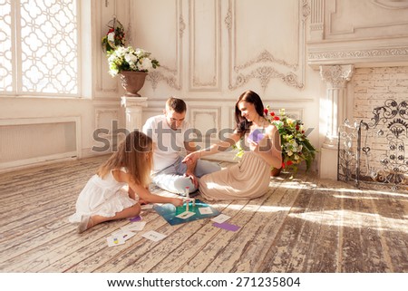 Beautiful family playing  funny boad game on floor in luxury living room