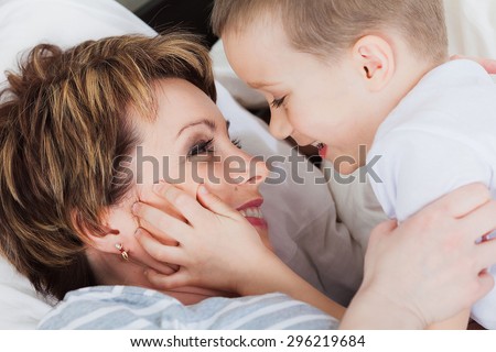 Happy child holding her mom in her bed in the Mother\'s day