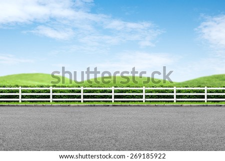 Side view of road, white fence and landscape