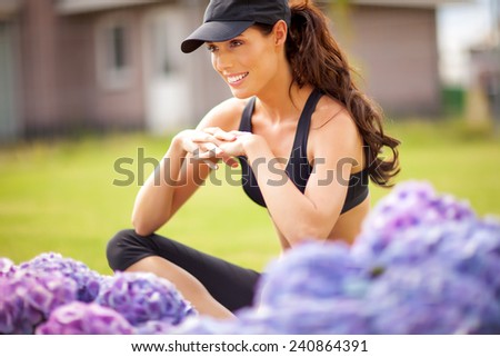 Young woman posing in fitness outfit in garden. Purple lush hydrangea and green grass downtown.