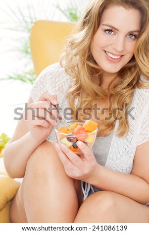 Young real woman with bowl of fresh fruits.