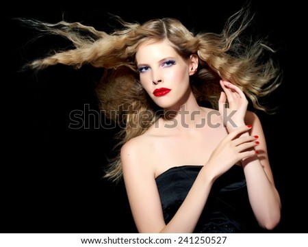 Model with blond hair wearing black silk cocktail dress on black background.