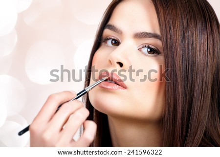 Woman applying lipstick with brush.