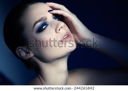 Model wearing blue glittery manicure and eye-shadow.