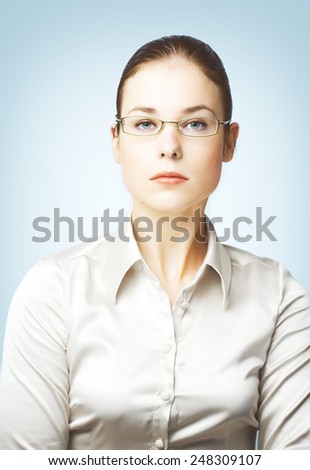 Portraits of young woman wearing glasses and silk blouse photographed on blue background.