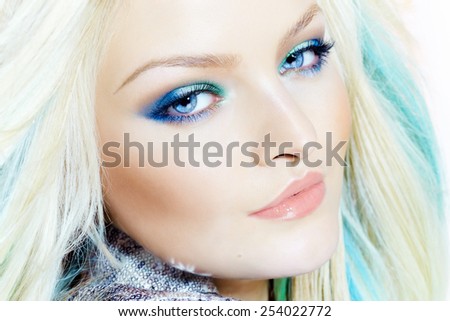 Closeup of a beautiful woman wearing makeup in cold tones and colored hair-extensions.