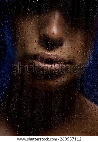 Female face behind wet window.