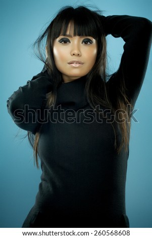 Asian fashion model with long messy hair wearing black knitwear.