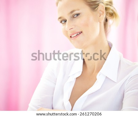 Caucasian forty year old woman wearing white formal blouse on pink background and smiling.