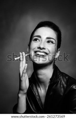 Black and white image of laughing smoking woman with cigarette.