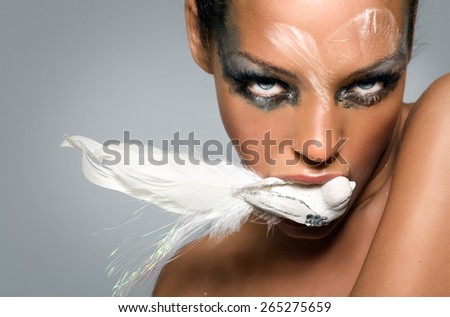 Beauty image of a fashion model with bird in her mouth.