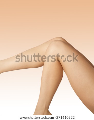 Two smooth tanned female legs over beige gradient background. Shaving, weight loss, skincare and hair removal concept.