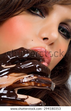 Closeup of a woman tasting dark chocolate from fingers.
