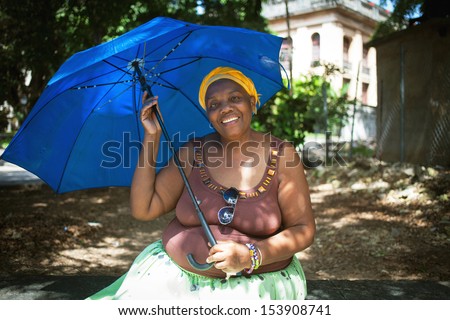 HAVANA, CUBA - JUNE 21: An unidentified woman with blue umbrella shelters herself from the heat in Havana, Cuba, June 21, 2013