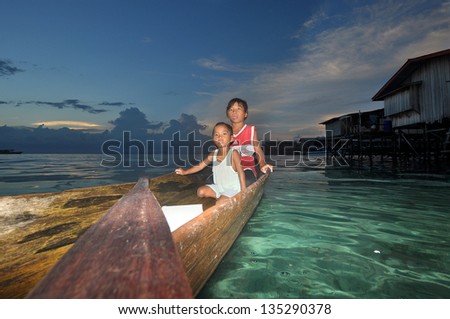MABUL ISLAND, SABAH, MALAYSIA - MARCH 3: local sea gypsy kid paddles a boat  March 3, 2013 in Mabul Island, Sabah, Malaysia. Children live here do not attend school for lack of means and resources