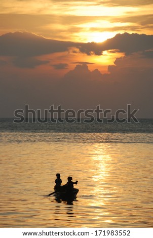 Sunset in mabul island with kids pedalling small boat  silhouette.Sabah, Malaysia