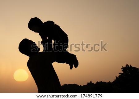 Silhouette of a man and his son with sunset background