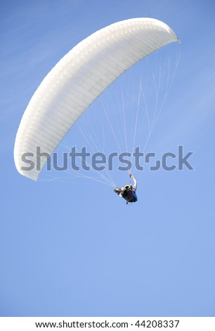 extreme active paraglider flyng over a blue sky
