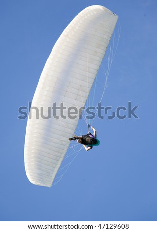 extreme active paraglider flying over a blue sky