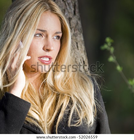 a young beautiful real girl talking with her mobile phone in the nature